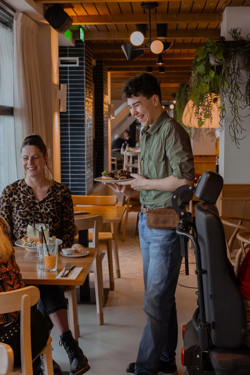 Een gast wordt aan tafel bediend in het restaurant van Groote Wielen