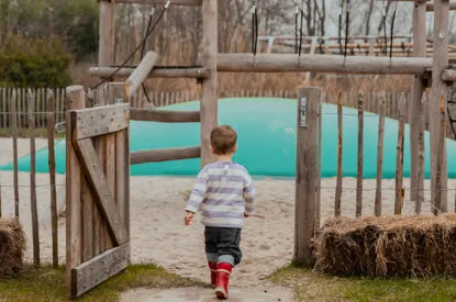 Een peuter loopt de speeltuin aan het water in